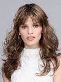 Perruque Pretty Hair Power : boucles Hollywood et frange épaisse, volume chic avec effet racines foncées ou balayage mix.