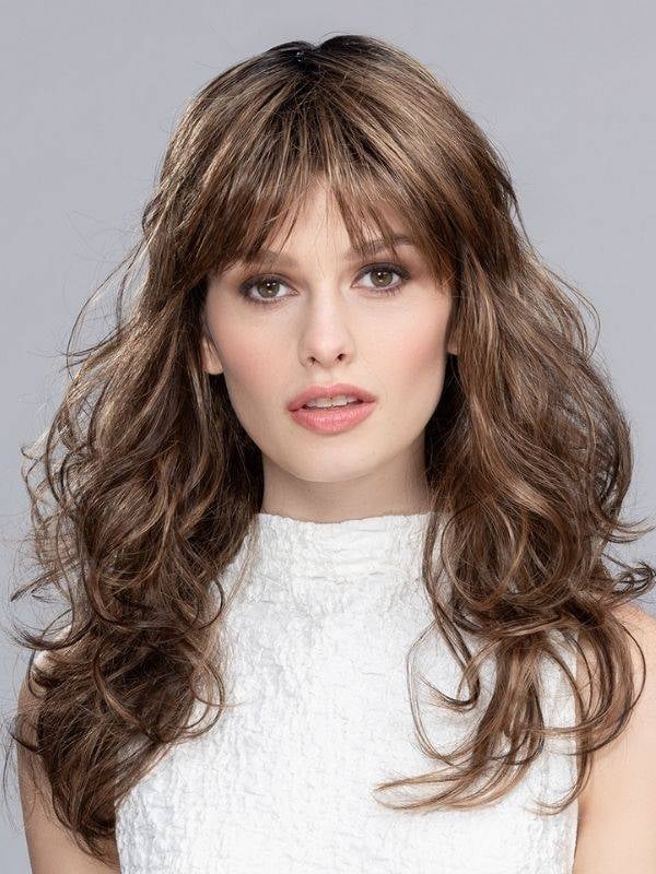 Perruque Pretty Hair Power : boucles Hollywood et frange épaisse, volume chic avec effet racines foncées ou balayage mix.