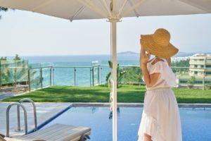 Femme avec un chapeau au bord de la piscine et avec vue sur la mère