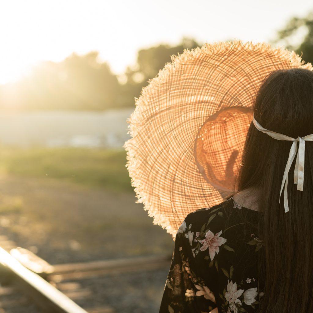 Femme qui cache le soleil avec un chapeau devant sa tête
